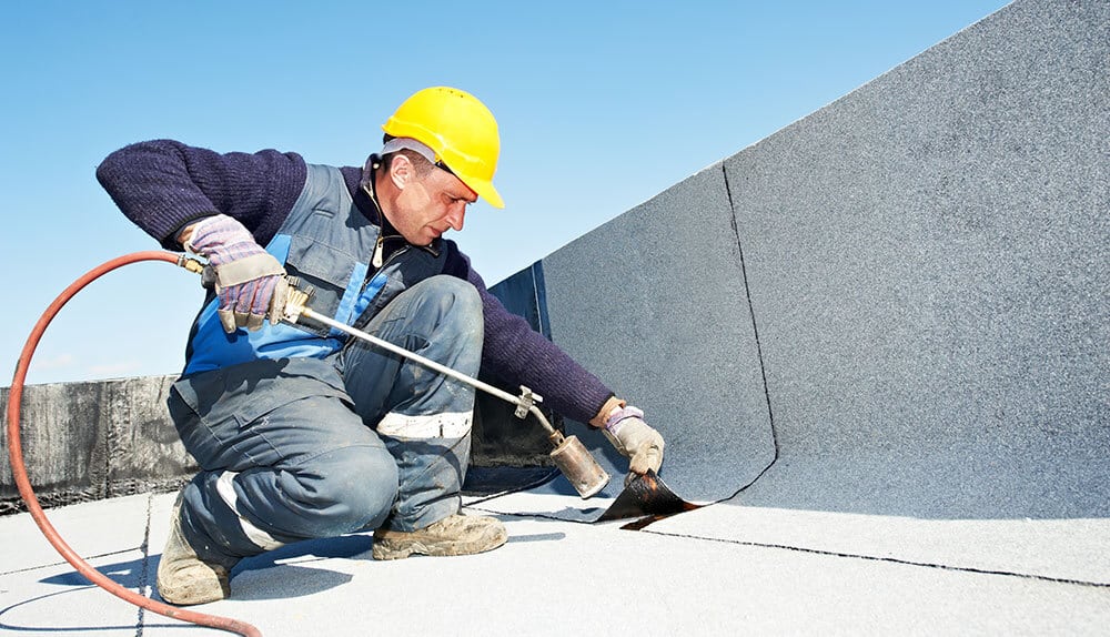 Building maintenance engineer repairing flat roof